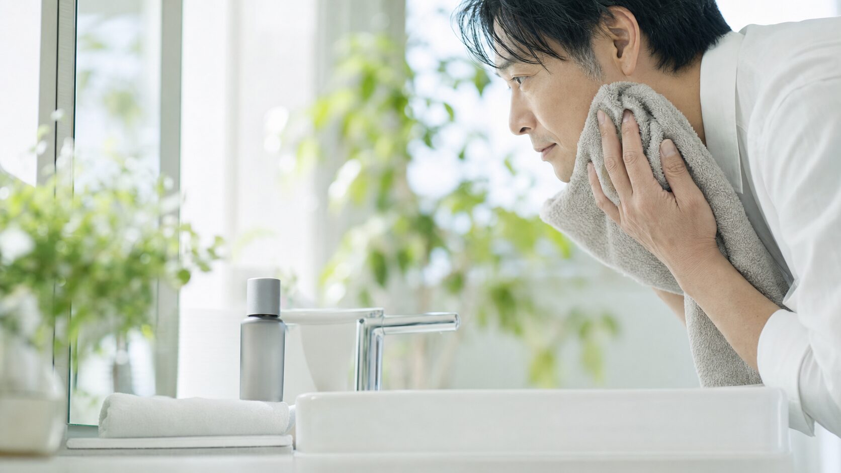 洗面台で顔まわりの清潔感を整える40代男性のイメージ