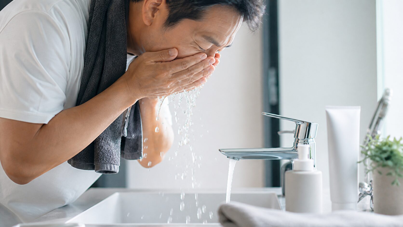 洗面台で洗顔をする40代男性のイメージ